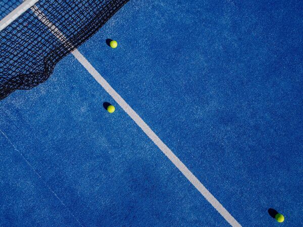 Drone aerial view of three balls in a blue paddle tennis court